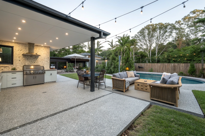 concrete-patio-entertainment-area Exposed aggregate concrete patio with outdoor furniture and BBQ area in Fraser Coast backyard